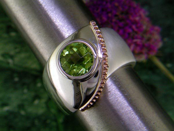 Brushed and polished sterling silver ring with peridot and 14K rose gold accent.